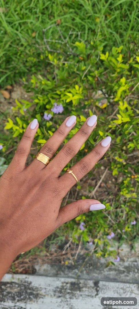 Hand with nails and rings against greenery