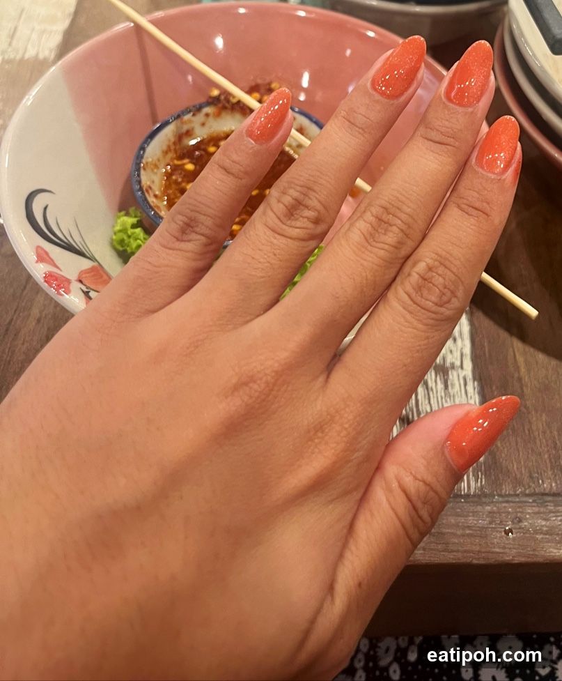 Hand with Orange Nails at Dining Table
