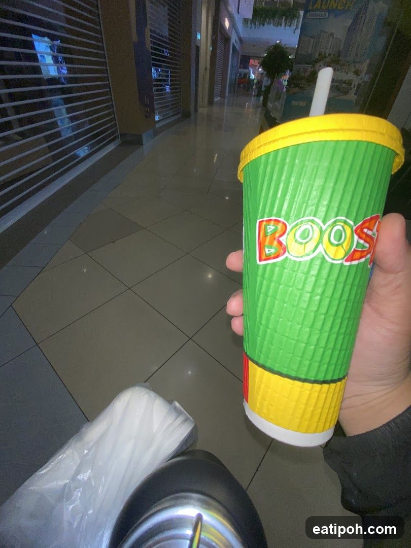 Hand holding Boost drink in shopping mall corridor