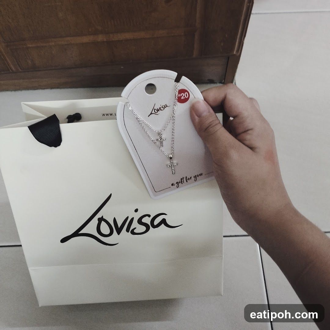 Hand holding Lovisa necklace with shopping bag