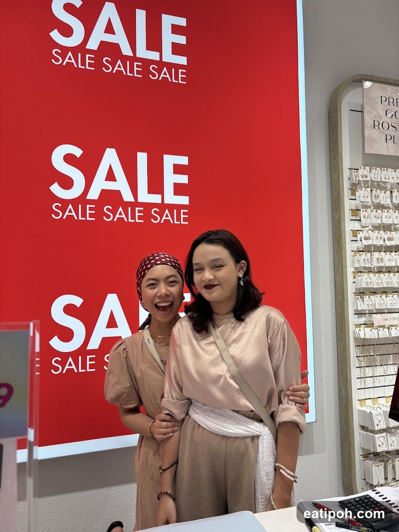 Two women posing in front of sale signage