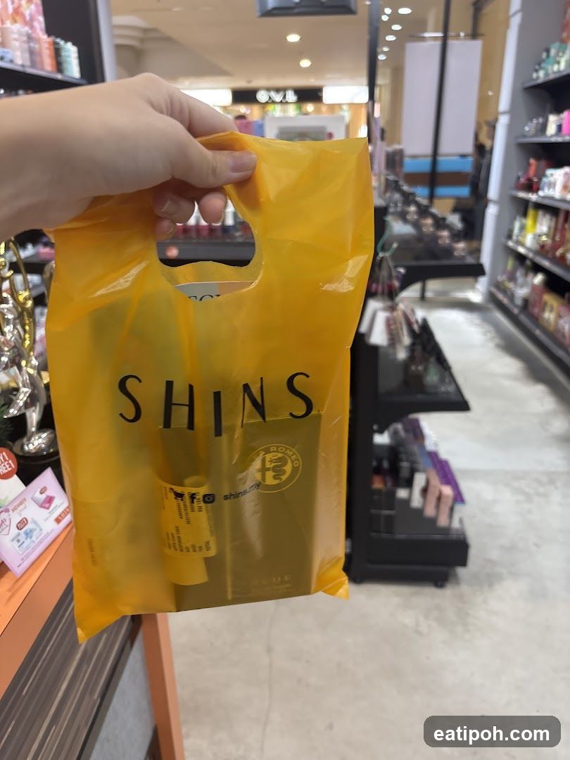 Hand holding SHINS shopping bag in store