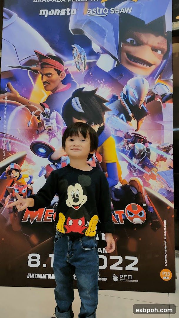 Child posing in front of promotional poster