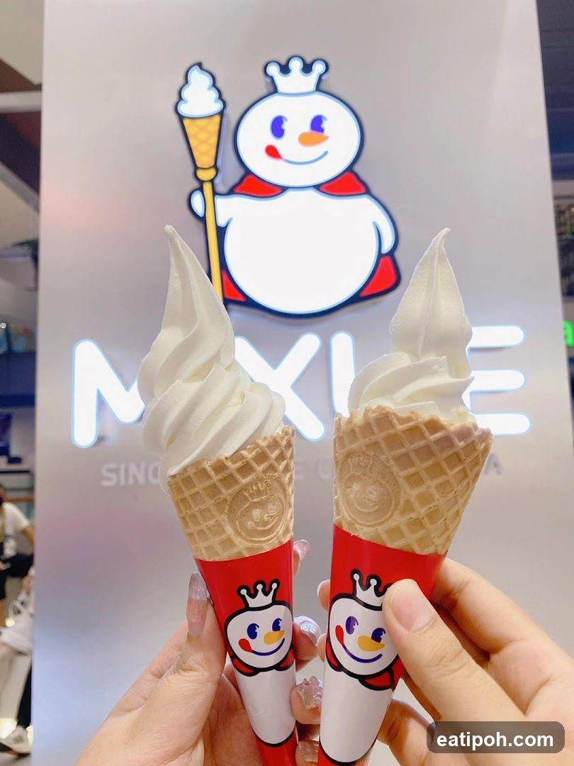 Hands holding ice cream cones in front of branded backdrop