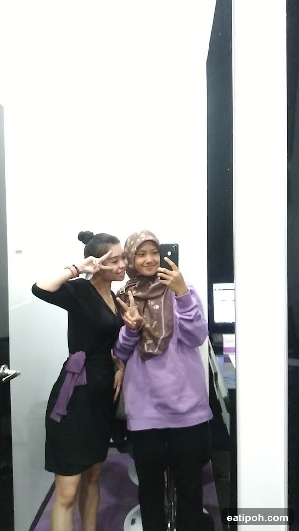 Two individuals taking selfie in mirror