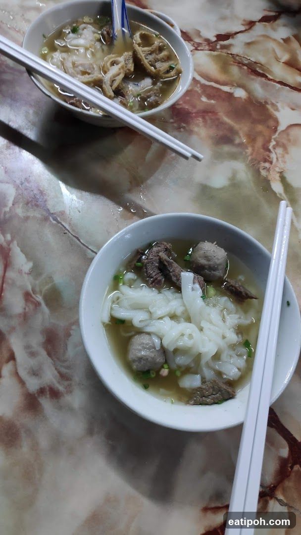 Two bowls of noodle soup on a marble table