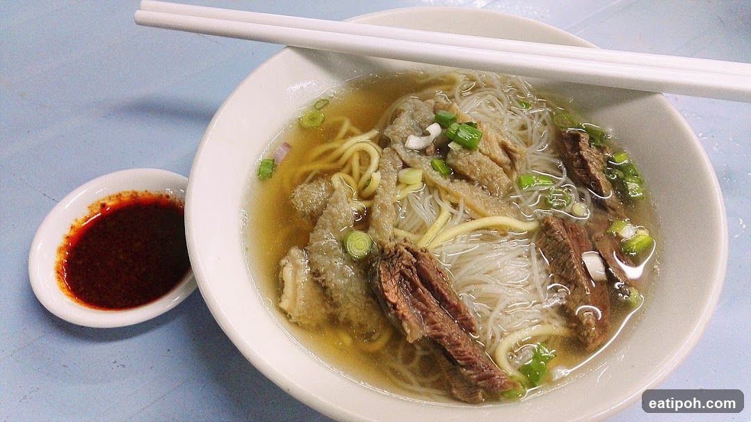Bowl of noodle soup with chopsticks and chili sauce