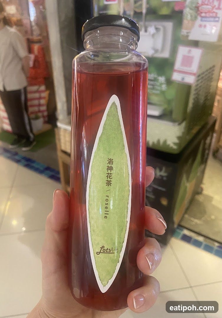 Hand holding a bottle of roselle tea