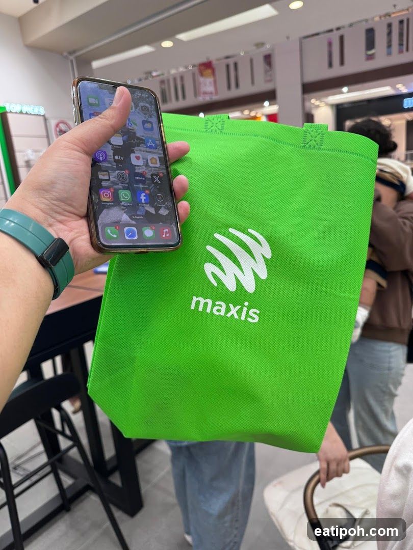 Person holding Maxis bag and phone inside a store