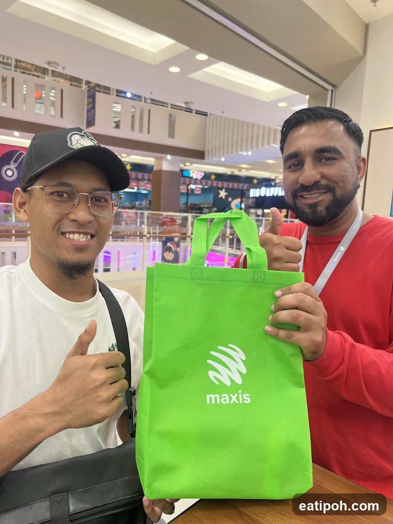 Two individuals holding a Maxis branded bag in a shopping mall