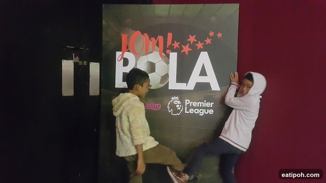 Two children posing in front of a promotional poster
