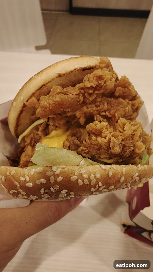 Hand holding fried chicken burger
