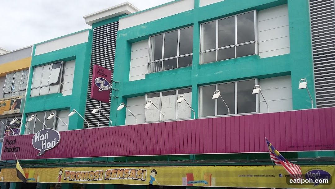 A two-story building with teal and white exterior walls, featuring a prominent magenta horizontal band with the 'Hori Hari' logo in a speech bubble. Multiple LED lights are mounted on the facade. A yellow banner below reads 'PROMOSI SENSASI!' with Malaysian flag and website details. The shop name is also displayed vertically on a red sign above the windows.