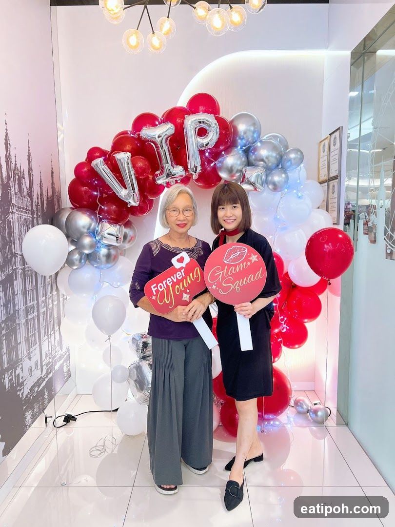 Two women posing in front of balloon arch