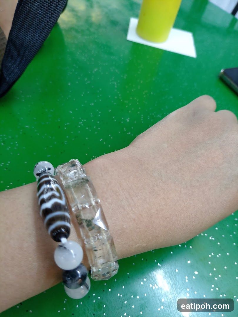 Hand wearing bracelets on green surface