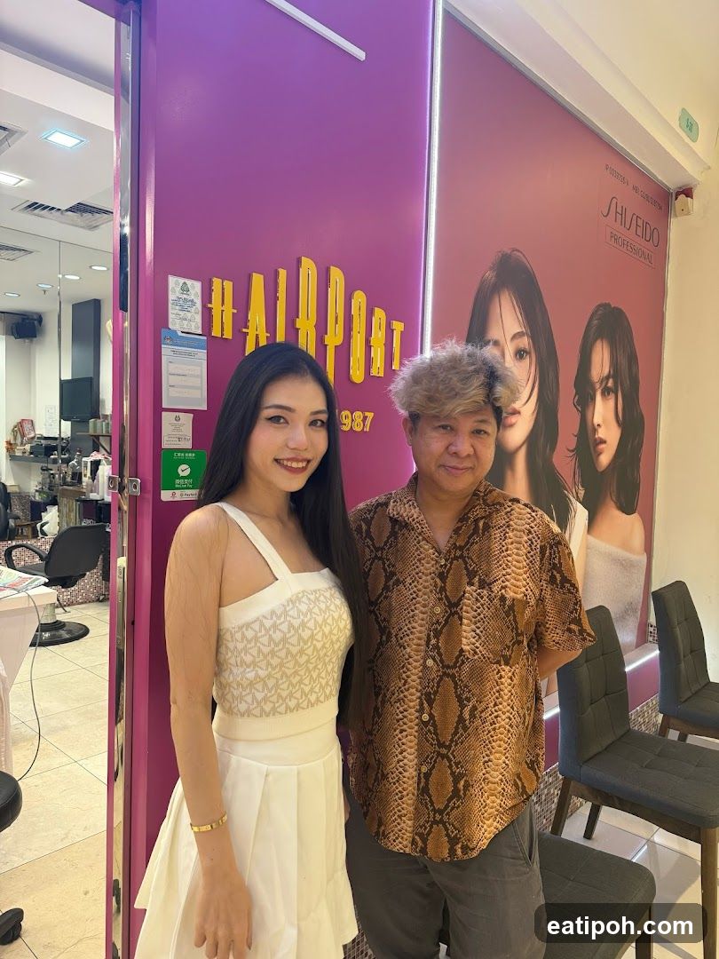 Two people posing in front of a hair salon entrance
