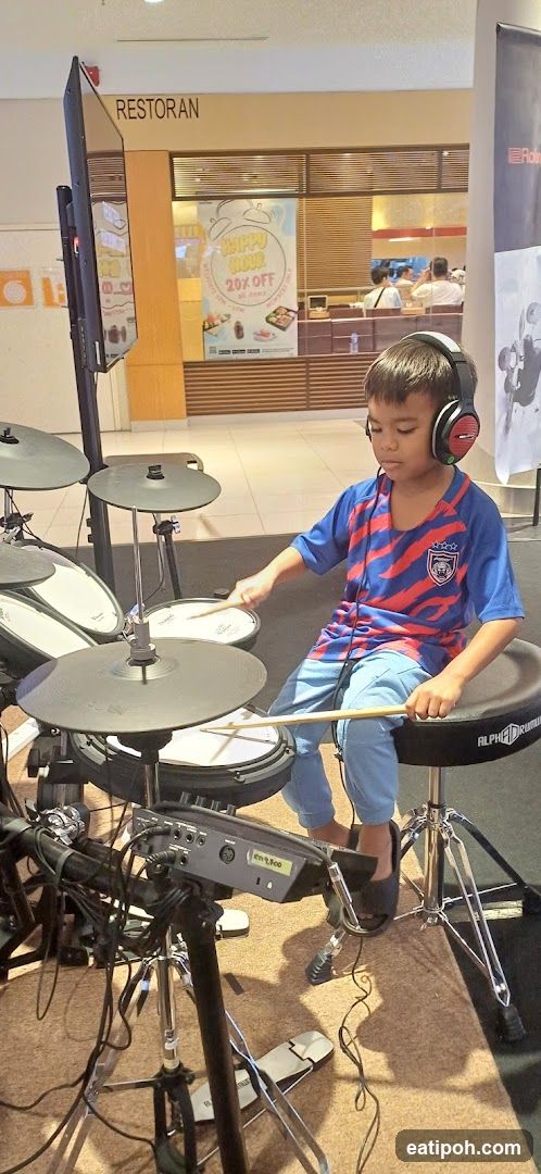Child playing electronic drum set in shopping mall