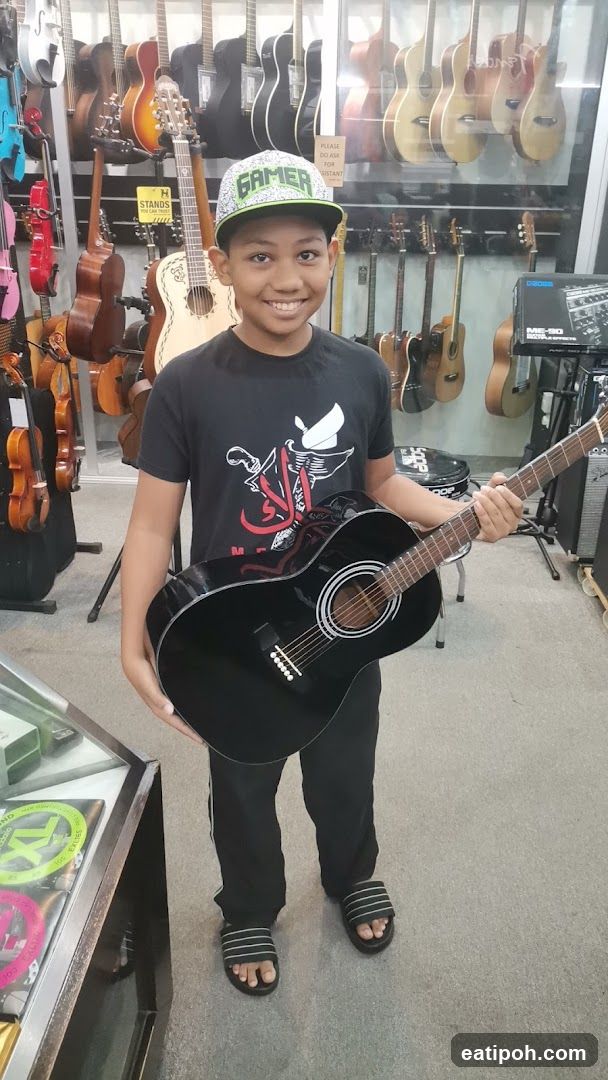 Child holding guitar in music store
