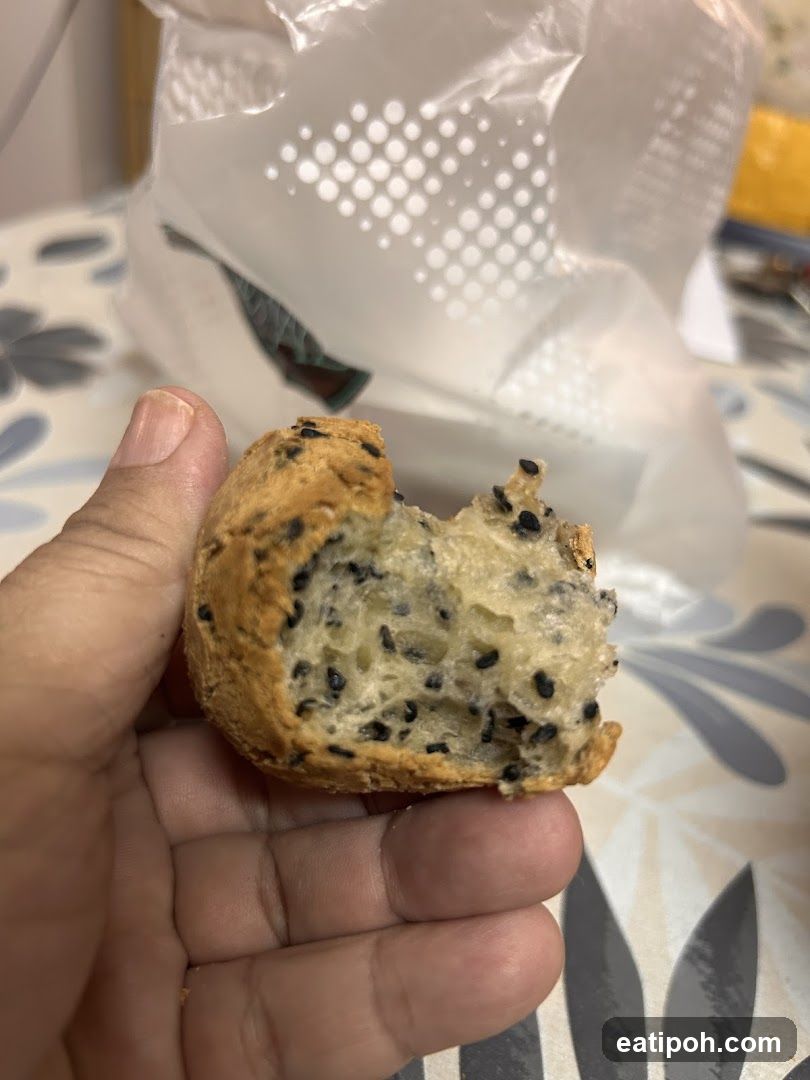 Hand holding a partially eaten sesame seed bread