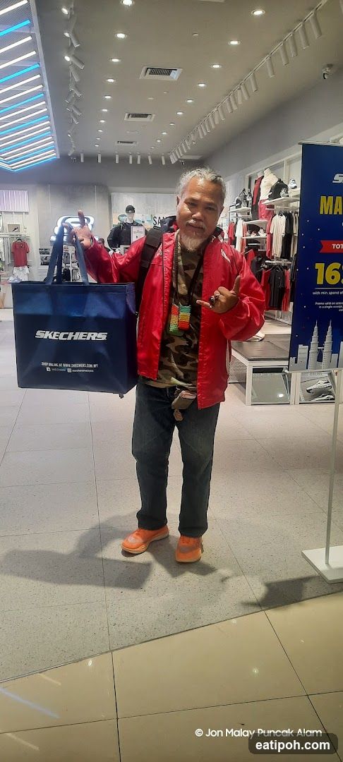 Man holding Skechers bag in store
