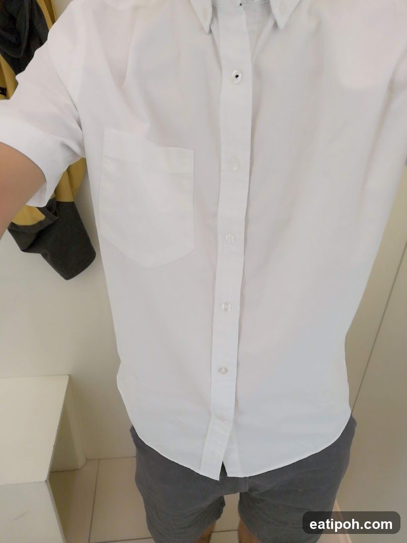 Person wearing a white button-down shirt and grey shorts