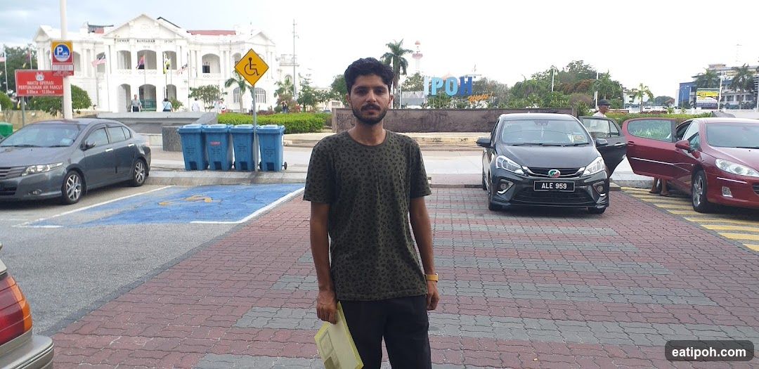 Man Poses in Front of IPOH Sign