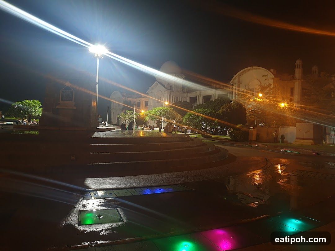 Nighttime view of a public square with illuminated buildings and a monument