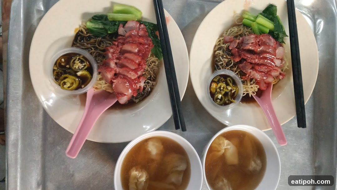 Two bowls of noodles with char siu and wonton soup