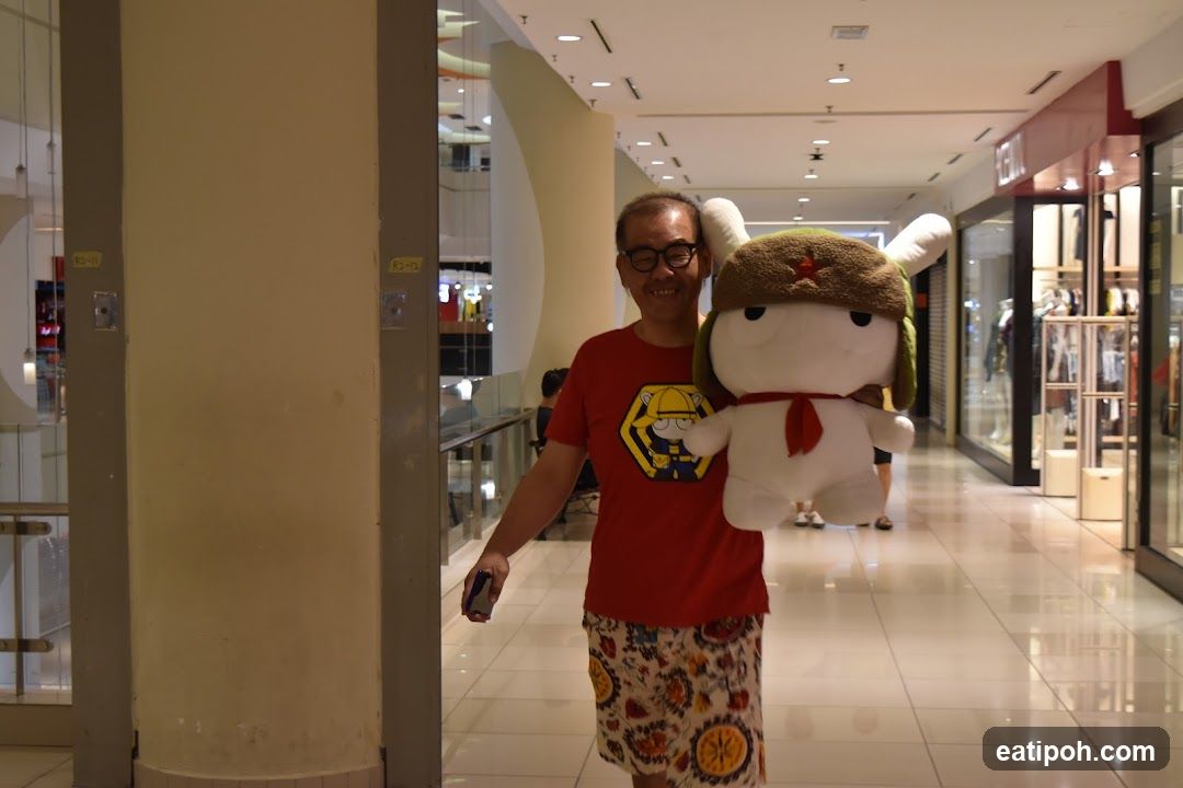 Man holding a large plush toy in a mall