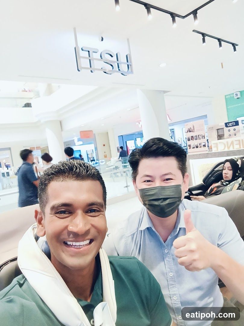 Two men posing for a selfie in a massage chair store