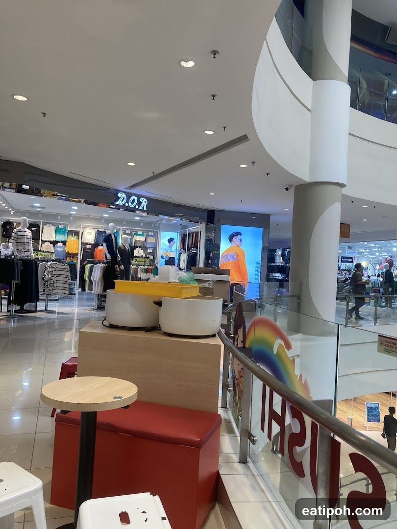 Interior of a shopping mall with clothing stores and seating areas.