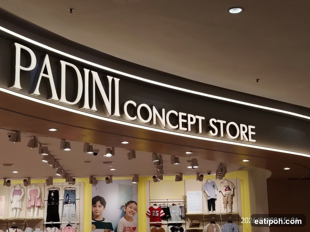The exterior signage of a Padini Concept Store is visible, with large white letters spelling out the name. Below the sign, clothing items are displayed on mannequins and racks. The store appears to be located indoors, possibly in a mall.